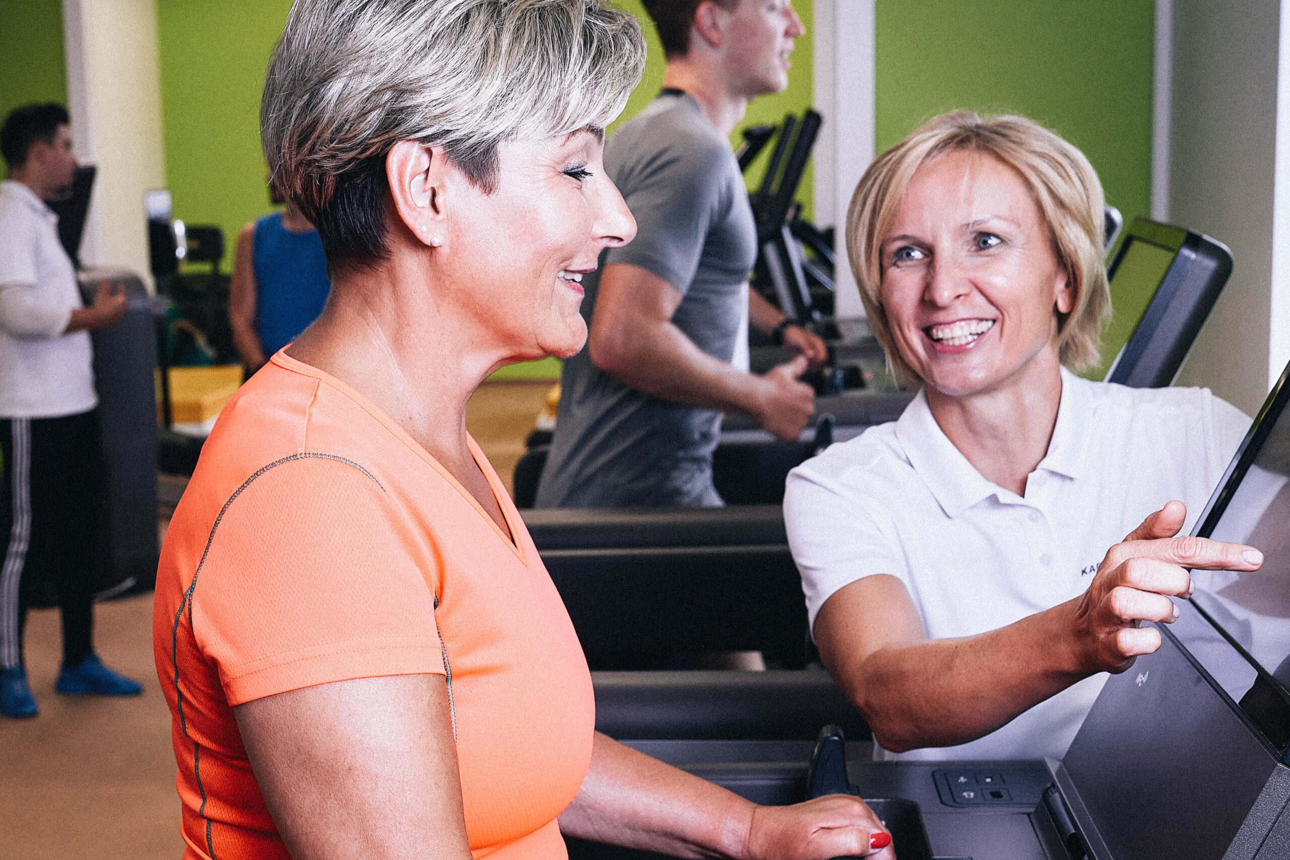 Trainerin mit Senioren beim training am Laufband